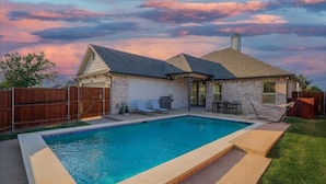 A backyard with a swimming pool, a covered patio, and a fenced area. - Trendy and Modern home w/ a Private Pool (Rowlett)