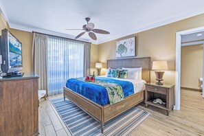 Une chambre d’hôtel avec un lit, une télévision, un ventilateur de plafond et un tableau au mur.