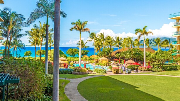 A resort with a pool area, palm trees, and a view of the ocean. - Beautiful Oceanfront Corner Unit - Honua Kai 215 (Lahaina)