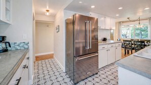 A modern kitchen with a stainless steel refrigerator, white cabinets, and patterned tile flooring. - Renton Oasis-Relaxing 3BR Home with Great Outdoor (Renton)
