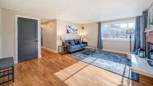 A modern living room with hardwood flooring, a grey sofa, a coffee table, and a fireplace. - Renton Oasis-Relaxing 3BR Home with Great Outdoor (Renton)