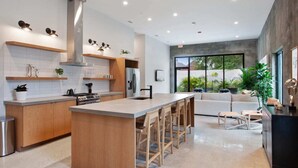 A modern kitchen with a central island, bar stools, and a dining area with a sofa and chairs. - Claudia | Sense of Calm and Relaxation,  Walking Distance to the Excitement - PO (New Orleans)