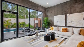 A modern living room with a pool view, a sofa, armchairs, and abstract wall art. - Claudia | Sense of Calm and Relaxation,  Walking Distance to the Excitement - PO (New Orleans)