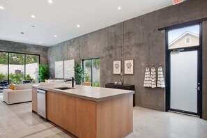 A modern kitchen with a central island, large windows, and a sliding glass door leading to a patio. - Claudia - Unit 5 | Sense of Calm and Relaxation, Walking Distance to the Excitem (New Orleans)