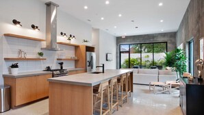 A modern kitchen with a central island, wooden cabinets, and bar stools. - Claudia - Unit 5 | Sense of Calm and Relaxation, Walking Distance to the Excitem (New Orleans)