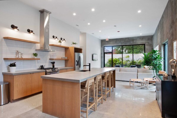 A modern kitchen with a central island, wooden cabinets, and bar stools. - Claudia - Unit 5 | Sense of Calm and Relaxation, Walking Distance to the Excitem (New Orleans)