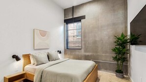 A modern bedroom with a bed, bedside tables, a window with blinds, a wall-mounted artwork, and a potted plant. - Claudia - Unit 4 | Sense of Calm and Relaxation, Walking Distance to the Excitem (New Orleans)
