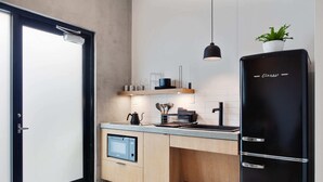 A modern kitchen with a black refrigerator, wooden cabinets, a built-in microwave, and a small countertop. - Claudia - Unit 4 | Sense of Calm and Relaxation, Walking Distance to the Excitem (New Orleans)