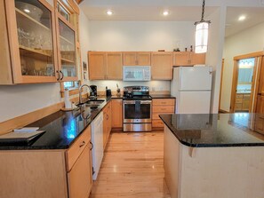 A kitchen with wooden cabinets, a stainless steel oven, a microwave, and a refrigerator.