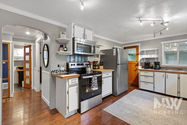 Kitchen features a central island with a stove, microwave, and oven, along with a refrigerator and cabinets.