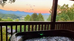 A hot tub with a view of mountains and greenery.