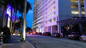 A high-rise hotel with multiple floors, a parking area, and palm trees. - *New* Elegant Apt Brickell 5 min. From Beach (Miami)