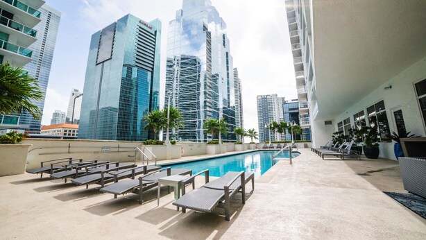 A rooftop pool area with lounge chairs, a swimming pool, and high-rise buildings in the background. - *New* Elegant Apt Brickell 5 min. From Beach (Miami)