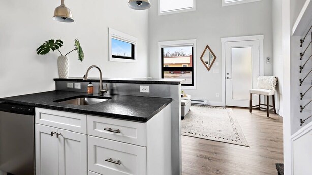 A modern kitchen with a central island, white cabinetry, and pendant lighting. - TC Loft Near Downtown w/ Open Layout (Traverse City)