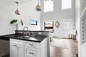 Une cuisine moderne dotée d’un îlot central, de meubles blancs et d’un éclairage suspendu.