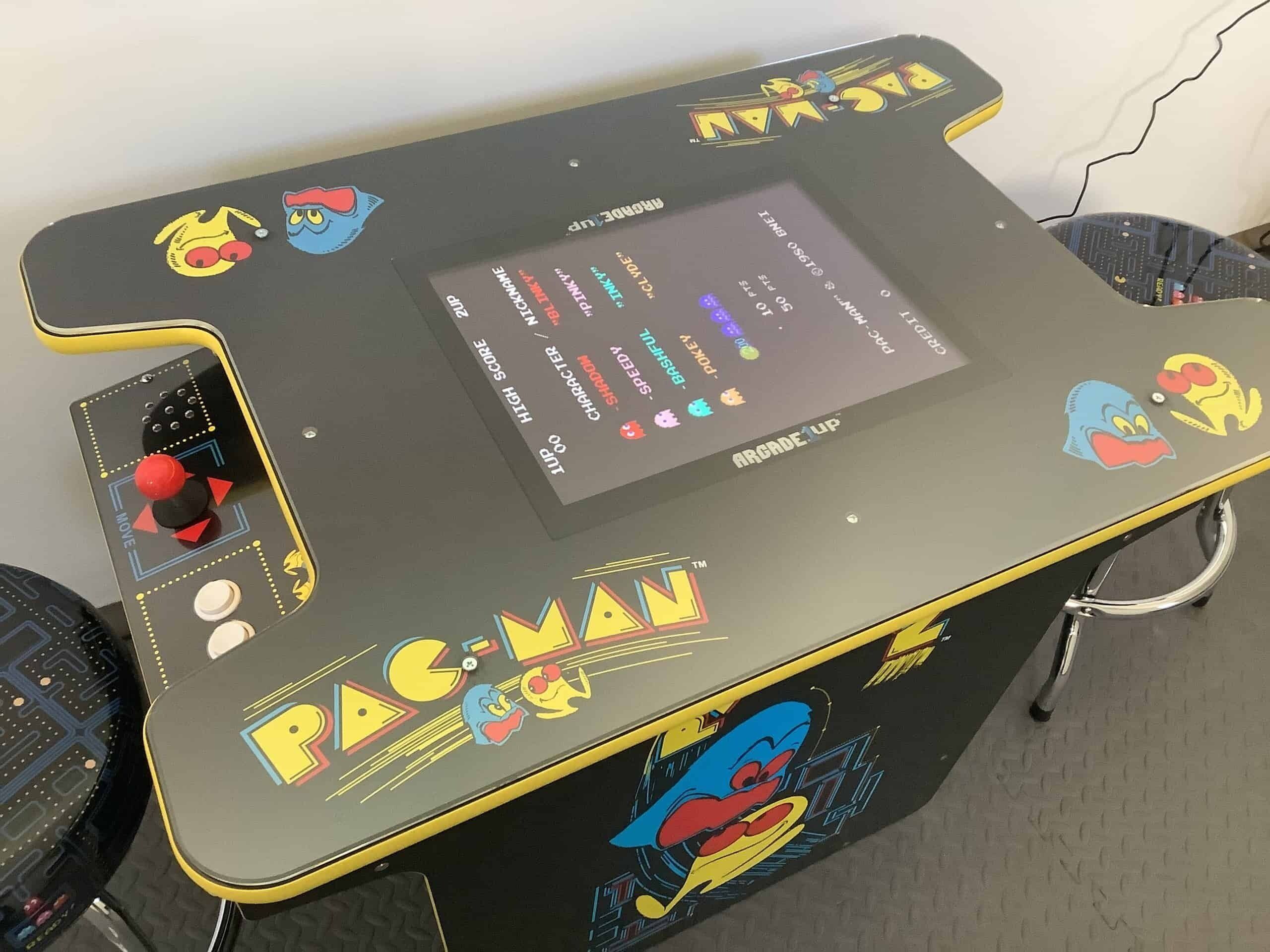 A Pac-Man arcade table with a joystick and a screen displaying game options.