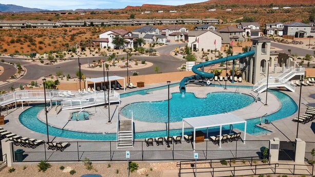 A resort with a swimming pool, a water slide, and a view of desert hills. - Paseos to Redrocks, HUGE REC ROOM! PICKLEBALL! (Washington)