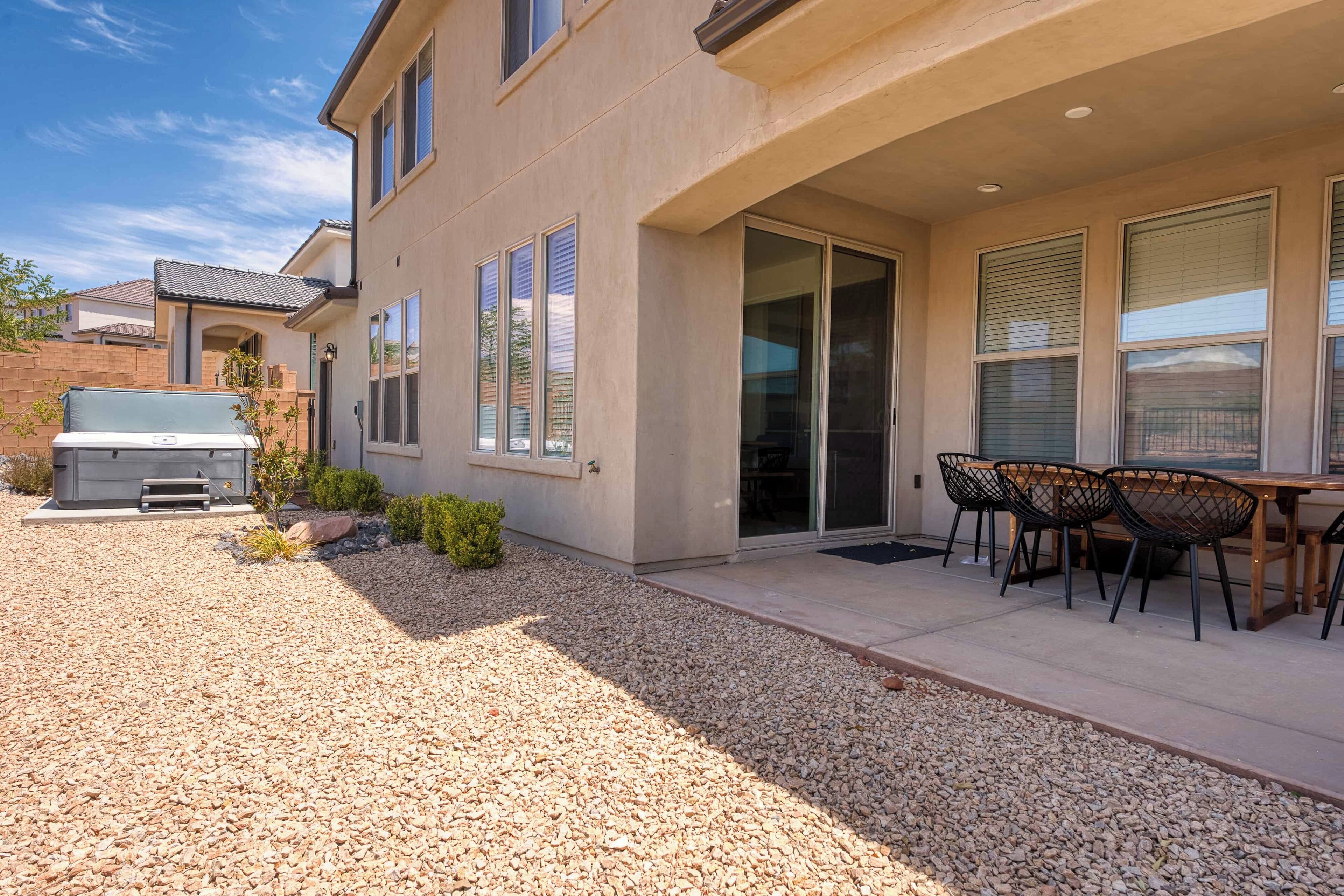 A residential building with a patio area, outdoor seating, and a barbecue grill.