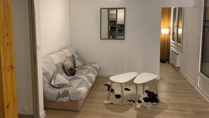 Een moderne woonkamer met een bank, een kleine tafel, een spiegel en een raam met uitzicht.
