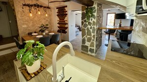 Une cuisine moderne agrémentée d’un pilier en pierre, de poutres en bois et d’un coin repas avec une horloge murale au style rustique.