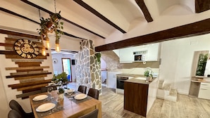Un coin repas avec une table en bois, des chaises et un mur décoratif en pierre.