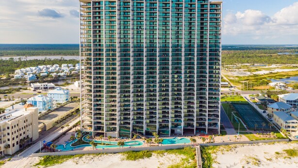 A high-rise hotel with multiple balconies, a swimming pool, and a view of the surrounding landscape. - The Oasis At Orange Beach 2706 by Liquid Life (Orange Beach)