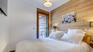 Une chambre avec un grand lit, des murs recouverts de panneaux de bois, un tableau et une table de chevet.