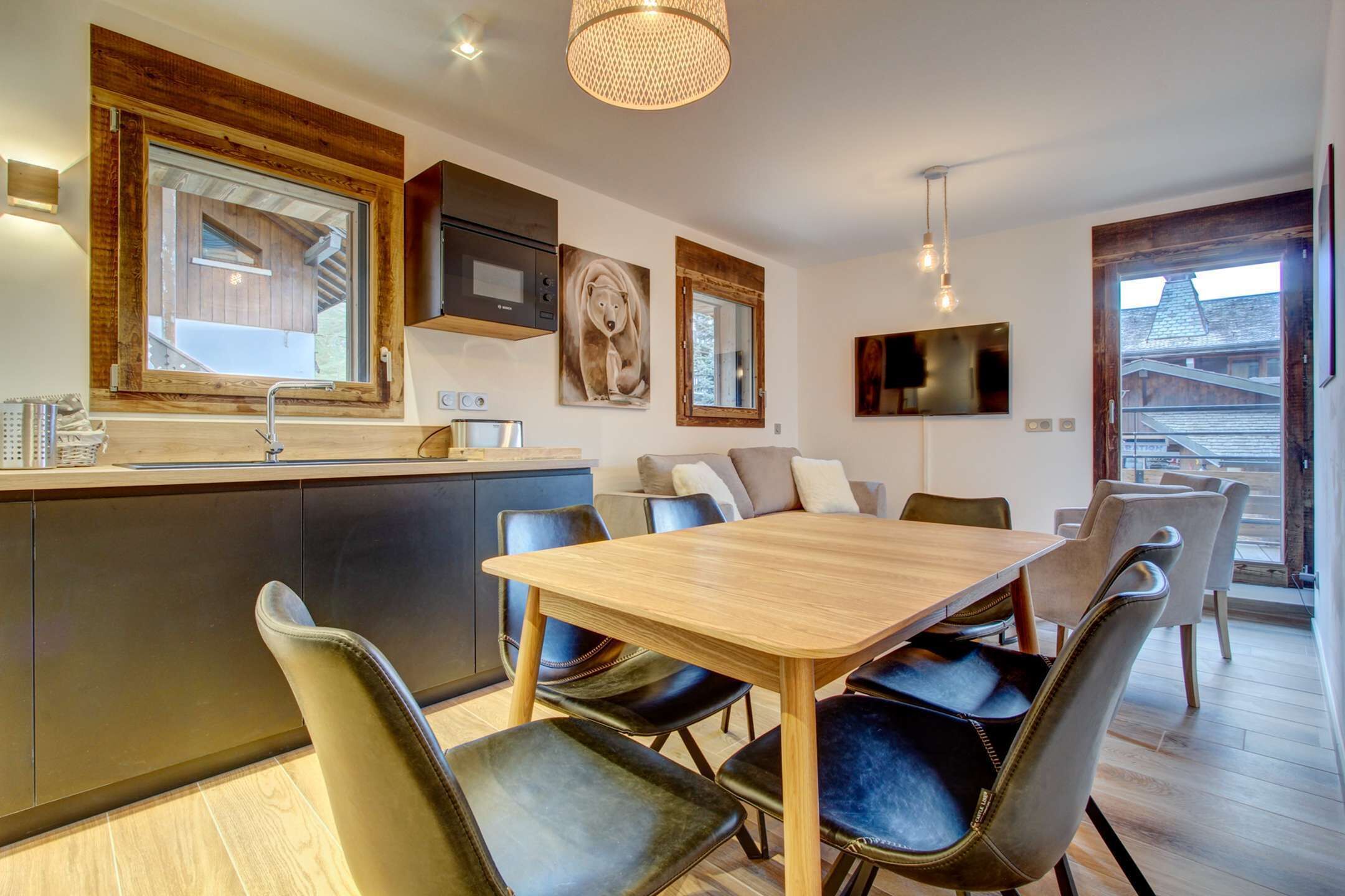 A modern kitchen with a wooden island, black leather chairs, and a dining table.