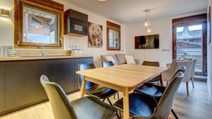 Une cuisine moderne avec un îlot en bois, des chaises en cuir noir et une table à manger.