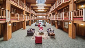 A spacious indoor area with wooden walls and a high ceiling, featuring multiple seating areas and a central fireplace.