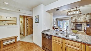 A modern kitchen with granite countertops, wooden cabinets, and a stone backsplash.