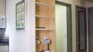 Une cuisine avec des meubles de rangement en bois, une fenêtre et une porte.