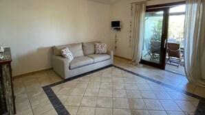 A living room with a sofa, a television, and a patterned rug. - Holiday Home just 1 km far from Porto Ainu Beach  (Sardegna)