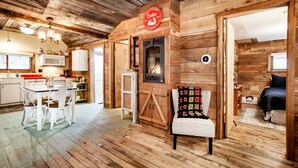 L’intérieur d’un chalet rustique comprend une cuisine, un coin repas et une cheminée accueillante.