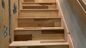 A wooden staircase with a handrail, leading to a landing with a framed picture. - Easy Access Cabin deep in the trails but very close to the city! (Murphy)