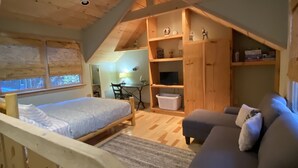 A cozy loft bedroom with a bed, a sofa, and a desk area. - Easy Access Cabin deep in the trails but very close to the city! (Murphy)