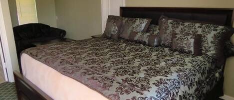 A bedroom with a large bed, a dark headboard, and a patterned bedspread.