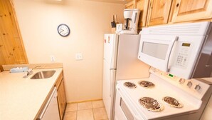 A compact kitchen with a sink, a refrigerator, a microwave, and a stove. - Condo in the mountains! (Red River)