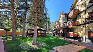 Un patio con una mesa de picnic de madera, un pabellón y un edificio con balcones.