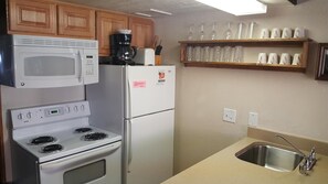 Compact kitchen with stove, refrigerator, and sink, offering ample storage and essentials for a comfortable stay.