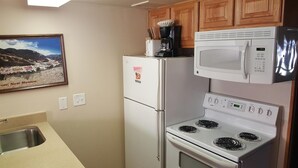 Une cuisine équipée d’un réfrigérateur, d’un four à micro-ondes, d’une cuisinière et d’un évier.