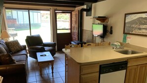 Une cuisine compacte équipée d’un lave-vaisselle, un coin repas avec une table et des chaises, et un salon avec un canapé et une table basse.