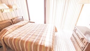 A bedroom with a bed, a wooden dresser, and a window with blinds. - Condo in the mountains! (Red River)