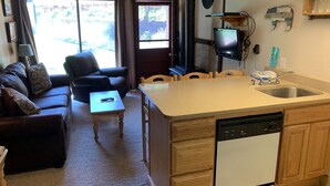 A compact living space with a kitchenette, a sofa, a dining table, and a TV. - Condo in the mountains! (Red River)