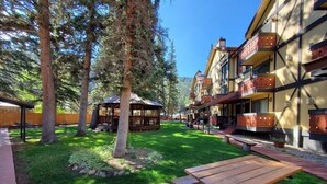 A courtyard with a wooden picnic table, a gazebo, and a building with balconies. - Condo in the mountains! (Red River)