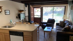 Uma cozinha compacta com lava-louças, armários de madeira e um espaço de refeições com cadeiras.