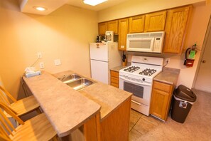 Compact kitchen with microwave, gas stove, refrigerator, sink, and faucet.