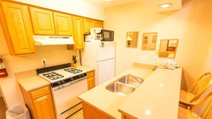 Una cocina compacta con armarios de madera, estufa, microondas y refrigerador.