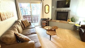 Un salon avec un canapé, une cheminée, un téléviseur et un balcon.
