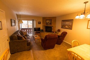 Relax by the fireplace in this inviting living room, featuring a sofa, armchairs, and a dining table.